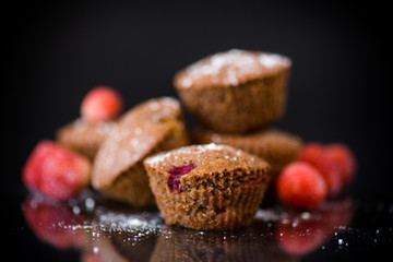 fresh sweet muffins with berries inside on black