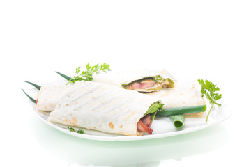 roll of pita with lettuce leaves, greens and sausage in a plate