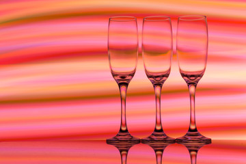 Three champagne glasses / flutes in a row with colorful multicolored light painting behind them