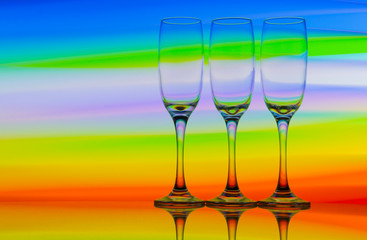 Three champagne glasses / flutes in a row with colorful multicolored light painting behind them