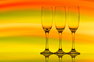 Three champagne glasses / flutes in a row with colorful multicolored light painting behind them