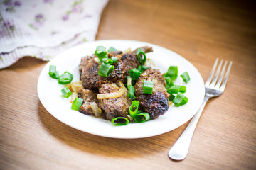 fried liver with onions in a plate on a wooden