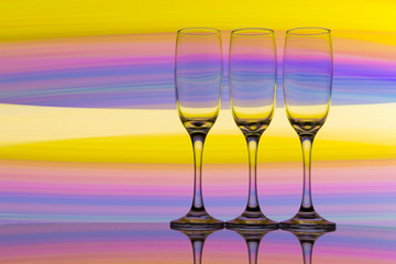 Three champagne glasses / flutes in a row with colorful multicolored light painting behind them