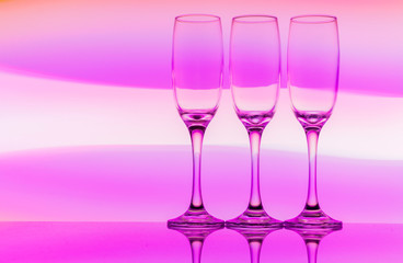 Three champagne glasses / flutes in a row with colorful multicolored light painting behind them