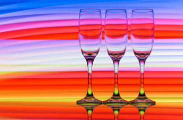 Three champagne glasses / flutes in a row with colorful multicolored light painting behind them
