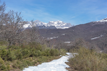 Fototapeta na wymiar Photograph of the top of the valley full of snow with the snowy mountains in the background in the area of Picos de Europa de Leon, Spain.