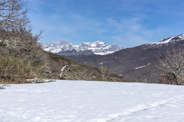 Photograph of the top of the valley full of snow with the snowy mountains in the background in the area of Picos de Europa de Leon, Spain.
