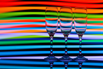 Three champagne glasses / flutes in a row with colorful multicolored light painting behind them