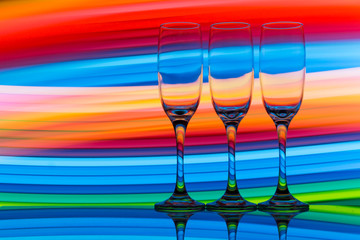 Three champagne glasses / flutes in a row with colorful multicolored light painting behind them