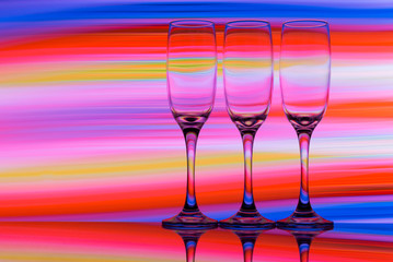 Three champagne glasses / flutes in a row with colorful multicolored light painting behind them