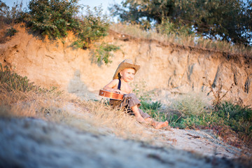 little boy playing guitar in summer