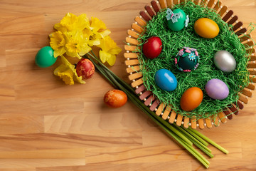 Top view of colorful easter eggs in basket with flowers