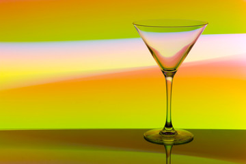 A cocktail / martini glass with colorful streaks of light painting behind