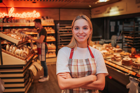 Happy young woman stand in grocery store. She pose nad look on camera. Happy worker smiling. Young m