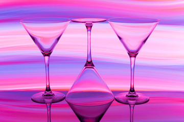 Three cocktail / martini glasses in a row with colorful streaks of light painting behind