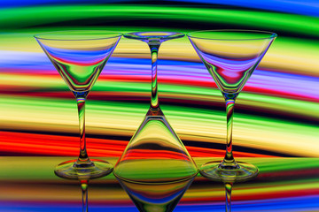 Three cocktail / martini glasses in a row with colorful streaks of light painting behind