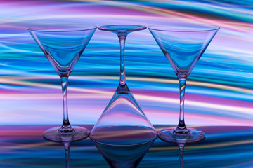 Three cocktail / martini glasses in a row with colorful streaks of light painting behind