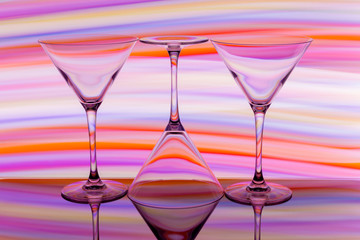 Three cocktail / martini glasses in a row with colorful streaks of light painting behind
