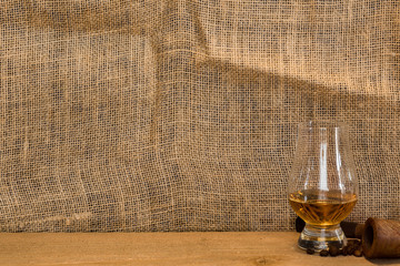Glencairn whisky glass and pipe against a burlap backdrop for mock ups and copy space