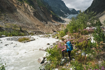 Naklejka na ściany i meble female traveler looking at flashy stream flowing in mountain valley