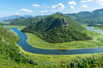 Naklejka na ściany i meble The picturesque meandering river flows among green mountains.