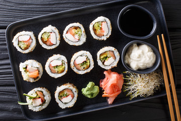 Uramaki rolls set served with sauces, soy sprouts, ginger and wasabi closeup on a plate. horizontal top view