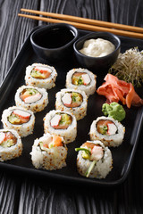 Uramaki rolls sushi served with sauces, ginger and wasabi closeup on a plate. vertical