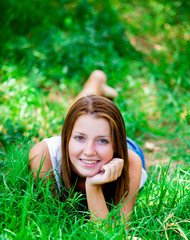 Beautiful teen girl in the park at green grass.
