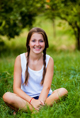 Beautiful teen girl in the park at green grass.