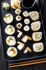 Japanese rolls Hosomaki, Uramaki, Maki, Nigiri, Tamagoyaki with various fillings close-up on a plate. Vertical top view