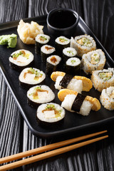 Japanese rolls Hosomaki, Uramaki, Maki, Nigiri, Tamagoyaki with various fillings close-up on a plate. vertical