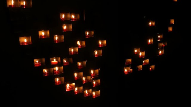 Burning beautiful red round prayer candles in a special niche in the darkness of a Catholic church