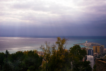 Fototapeta na wymiar View of the Mediterranean Sea in the Spanish city of Malaga. Bright sun rays make their way through the clouds. Amazing morning.