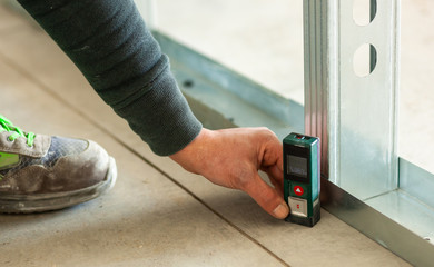 Hand holding an accurate laser meter on the floor.
