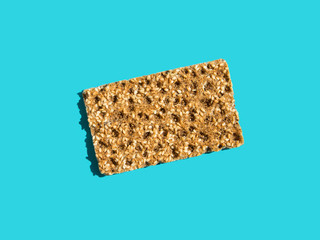 One scandinavian rye whole grain crispbread with sesame seeds on solid blue background. Harsh shadows hard light. Trendy minimalist pop art style. Balanced diet fiber slow carbs concept.