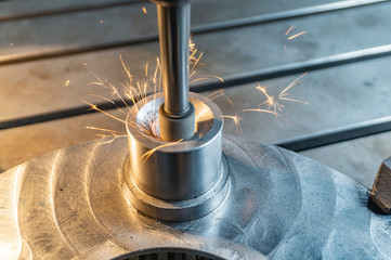 Internal processing of the hole with an abrasive stone on a vertical grinding machine, sparks fly in different directions.