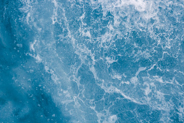 Pale blue sea surface with waves, splash,  foam and bubbles at high tide and surf, abstract background