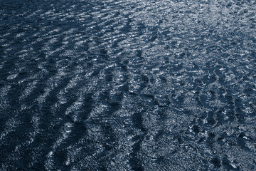 Background, texture from dark waves, in which the sun reflects. Dark waves on the surface of the...