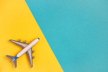 Flat lay airplane on yellow and blue background. Concept travel.