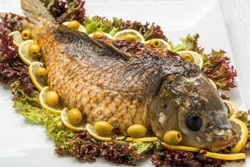Stuffed fish with lettuce leaves. On table with large silver candlestick