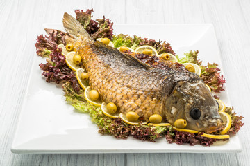 Stuffed fish with lettuce leaves. On table with large silver candlestick