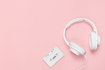 White cassette tape and headphones on a pink background. Party 90s concept.