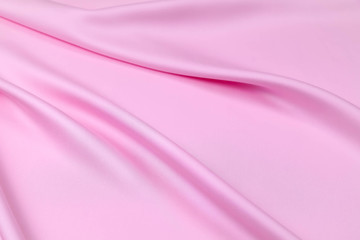 Pink saturated plastic fabric is laid by diagonal soft folds