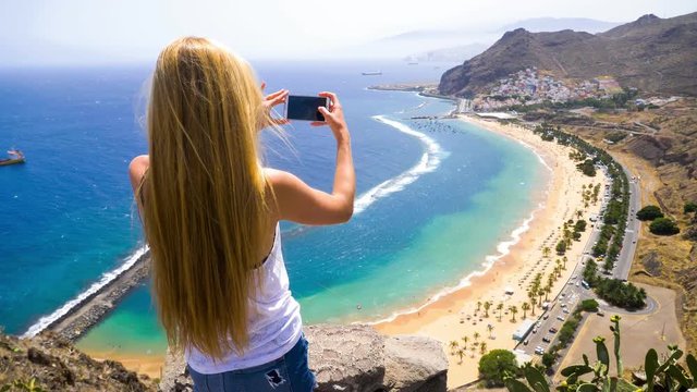 A woman taking pictures of Las Teresitas beach on Tenerife