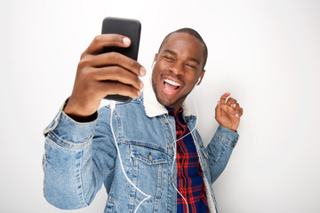 happy young black guy listening to music with smart phone and earphones and dancing