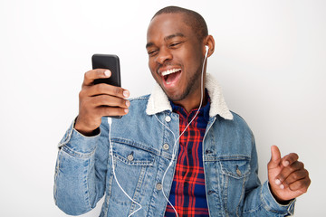 Close up happy young black guy listening to music with smart phone and earphones