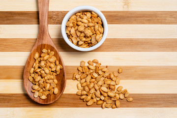 Roasted soybeans in wooden spoon and pot on bamboo striped table.