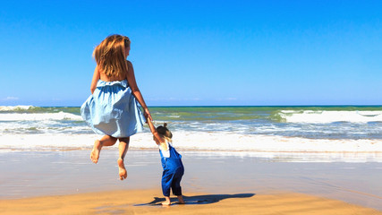 Mother and daughter having fun on the beach at sunny day.