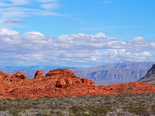 view of red rocks and mountains with clouds and sky in valley of fire