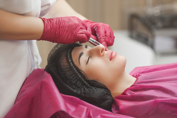 Cosmetologist making an ingection to her client. Woman beauty procedure, lip augmentation...